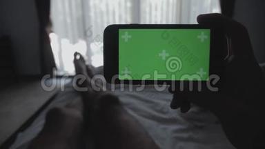 合上躺在床上的年轻人手里拿着智能手机绿色屏幕彩色键绿色屏幕分享真实的社交